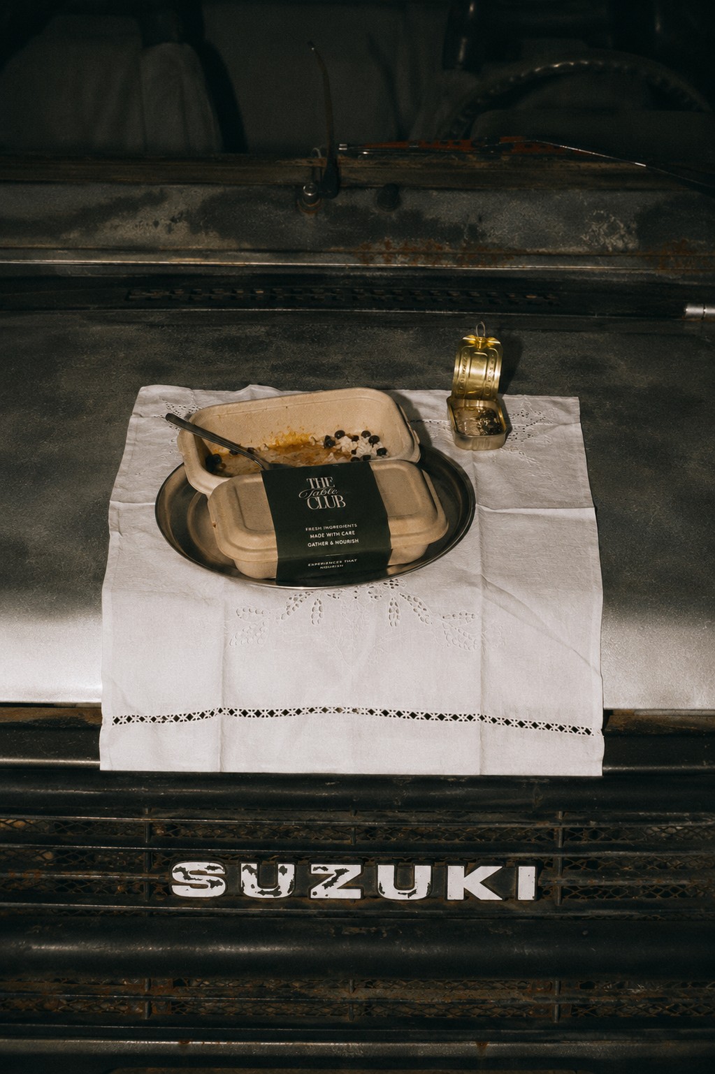 A Table Club meal box on a linen napkin, set on the tailgate of a vintage Suzuki truck
