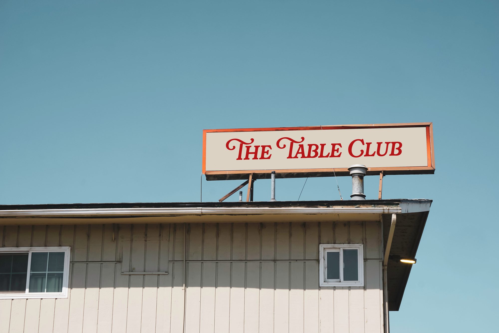 The Table Club sign mounted on the rooftop of the building, against a clear sky
