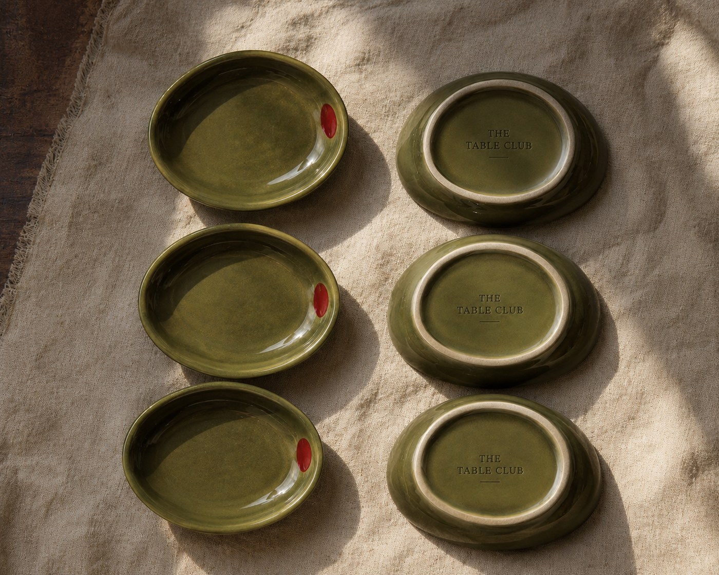 Three olive-green ceramic dishes, hand-stamped with The Table Club mark