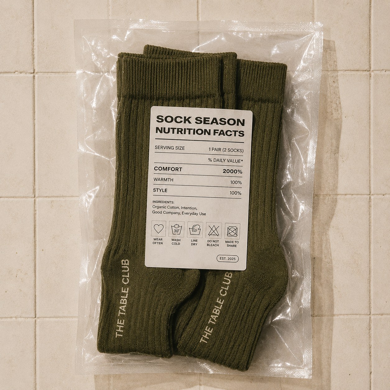 A pair of olive-green ribbed Table Club socks, packaged with a nutrition-label-style tag